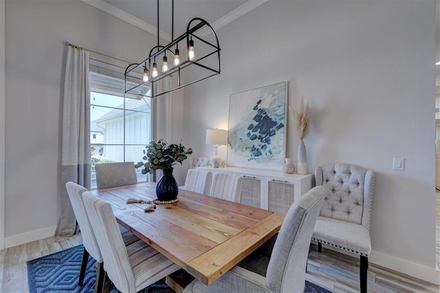 dining area with crown molding, an inviting chandelier, and light wood-type flooring