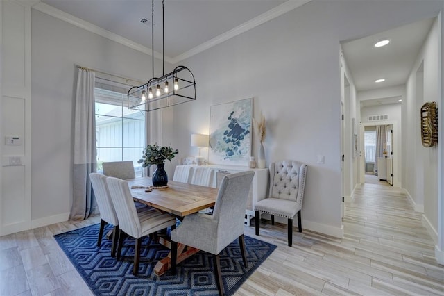 dining space with ornamental molding and light wood-type flooring