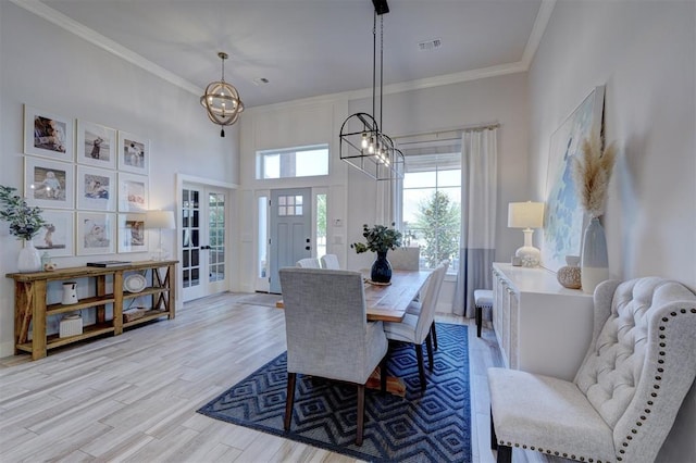 dining room with a notable chandelier, crown molding, and light hardwood / wood-style flooring