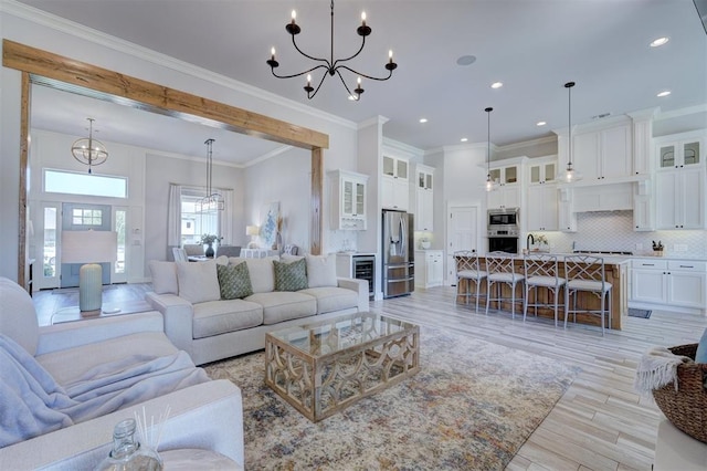 living room featuring crown molding, sink, a chandelier, and light hardwood / wood-style floors