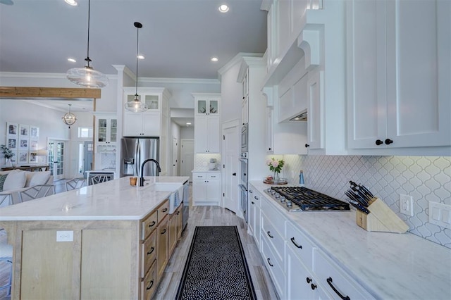 kitchen with stainless steel appliances, a center island with sink, pendant lighting, and white cabinets