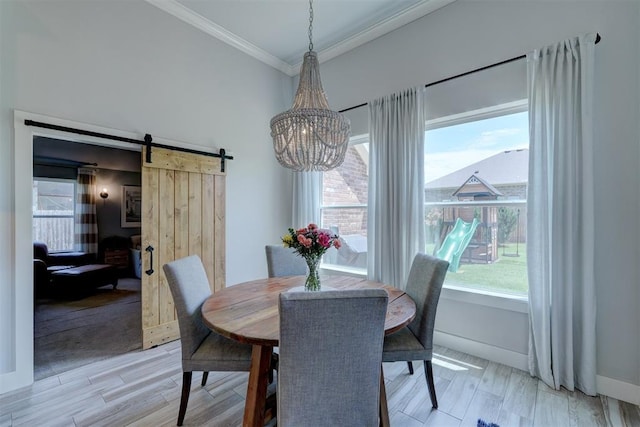 dining space featuring a notable chandelier, crown molding, a barn door, and light wood-type flooring