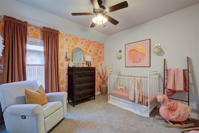 bedroom with vaulted ceiling, a nursery area, carpet floors, and ceiling fan