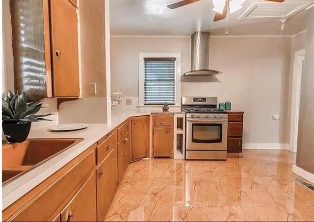 kitchen featuring sink, ornamental molding, ceiling fan, gas stove, and wall chimney exhaust hood