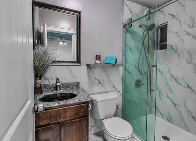 bathroom featuring an enclosed shower, vanity, tile walls, and toilet