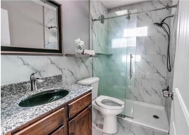 bathroom featuring vanity, a shower with door, and toilet