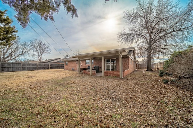 back house at dusk featuring a lawn and a patio area