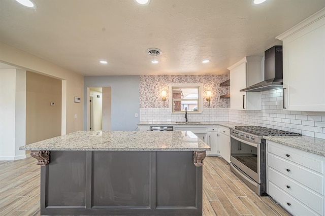 kitchen featuring white cabinets, stainless steel appliances, and wall chimney range hood