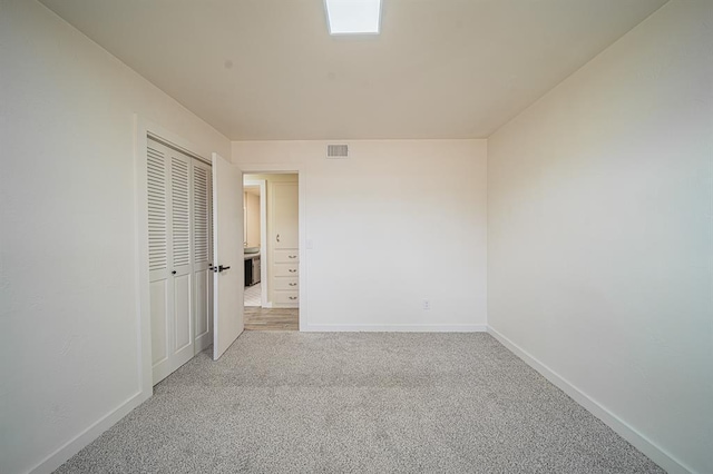 unfurnished bedroom with light colored carpet and a closet