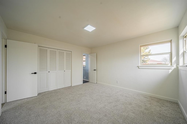 unfurnished bedroom featuring multiple windows, carpet flooring, and a closet