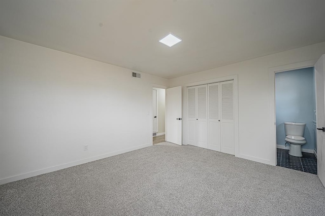 unfurnished bedroom with ensuite bathroom, a closet, and carpet flooring