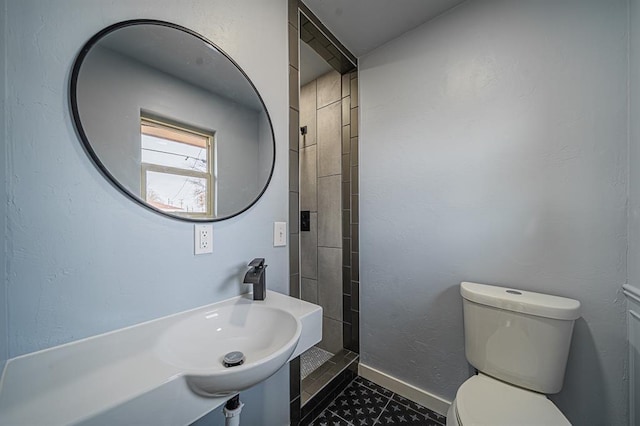 bathroom featuring tile patterned flooring, toilet, and tiled shower