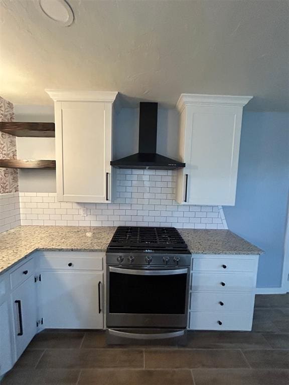 kitchen featuring light stone countertops, stainless steel range with gas stovetop, wall chimney range hood, and white cabinets