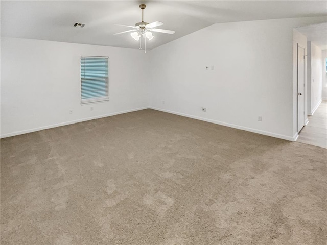 empty room with ceiling fan, vaulted ceiling, and light carpet