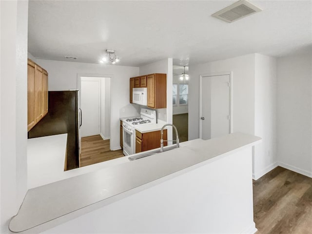 kitchen with sink, white appliances, dark hardwood / wood-style floors, and kitchen peninsula