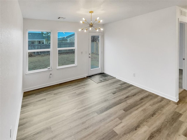 unfurnished dining area with a notable chandelier and light hardwood / wood-style floors