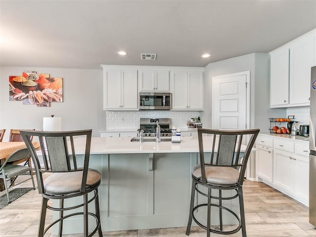 kitchen featuring white cabinetry, appliances with stainless steel finishes, and a center island with sink