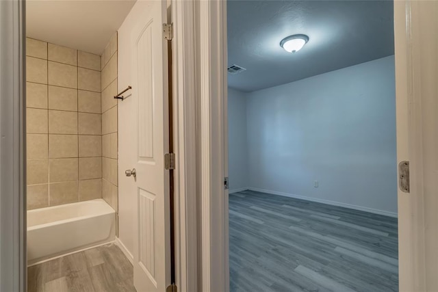 bathroom with hardwood / wood-style floors and tiled shower / bath combo