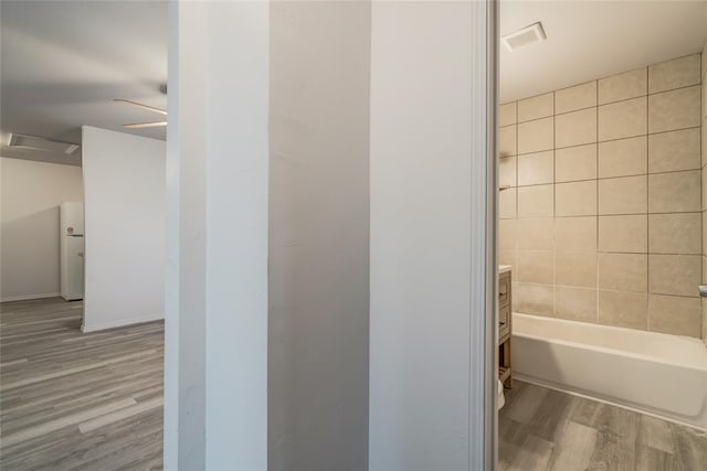 bathroom featuring tiled shower / bath combo, wood-type flooring, and vanity