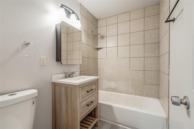 full bathroom featuring vanity, tiled shower / bath combo, and toilet