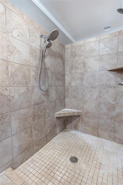 bathroom with crown molding and a tile shower