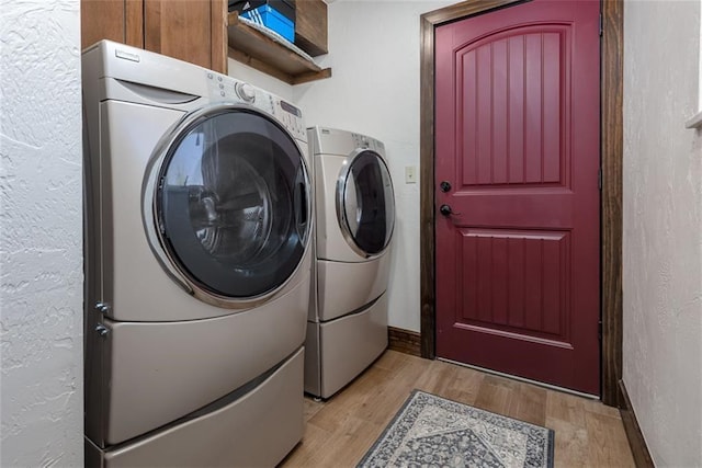 laundry room featuring cabinets, washer and dryer, and light hardwood / wood-style floors