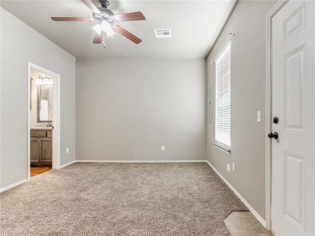 interior space featuring light carpet, connected bathroom, sink, and ceiling fan