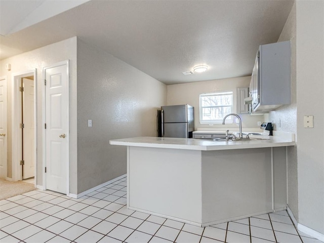 kitchen featuring stainless steel refrigerator, kitchen peninsula, and sink