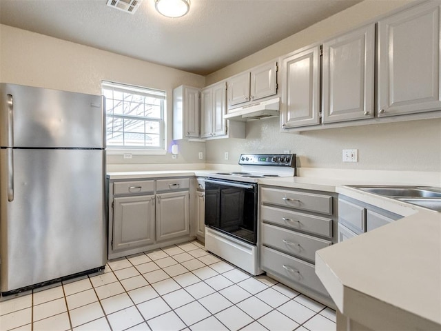 kitchen featuring light tile patterned floors, stainless steel fridge, gray cabinets, electric range, and a textured ceiling