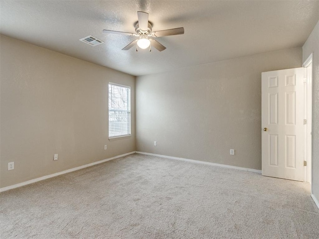 spare room featuring a textured ceiling, light colored carpet, and ceiling fan