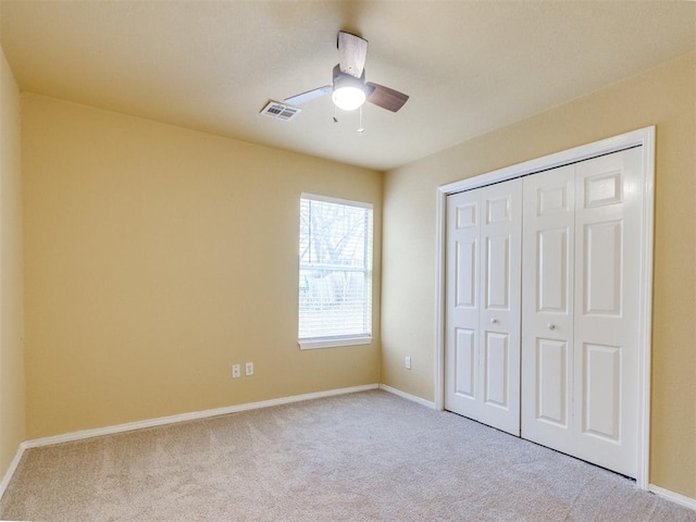 unfurnished bedroom with ceiling fan, light colored carpet, and a closet