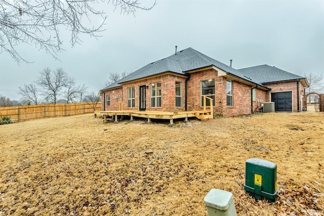 rear view of house featuring a garage, a wooden deck, and central AC