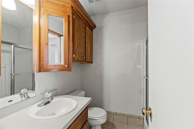 bathroom featuring walk in shower, vanity, toilet, and tile patterned flooring