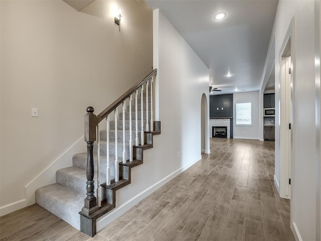 staircase featuring wood-type flooring and ceiling fan