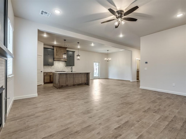 unfurnished living room with wood-type flooring, sink, and ceiling fan with notable chandelier