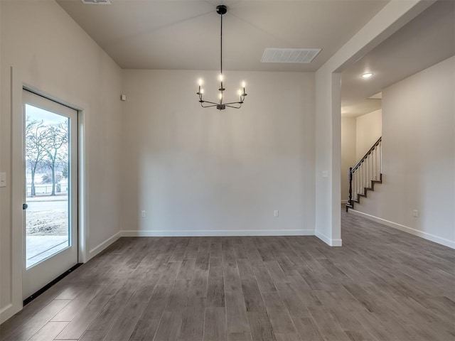 spare room with an inviting chandelier and wood-type flooring