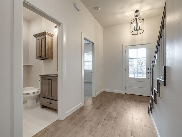 doorway to outside with a notable chandelier and light wood-type flooring