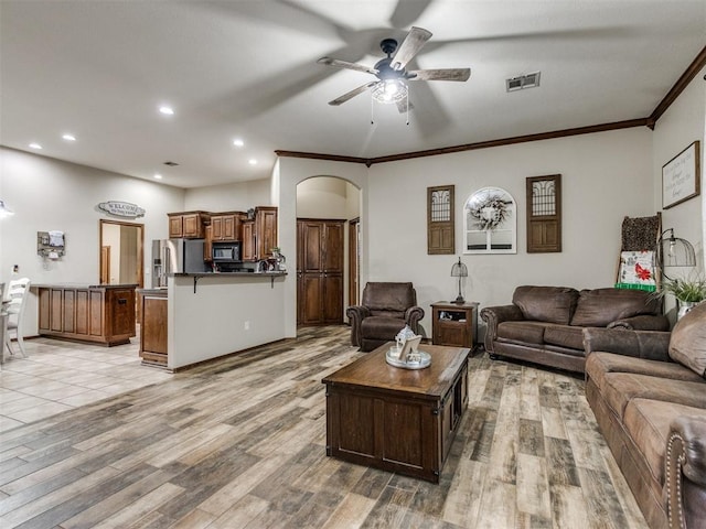 living room with ceiling fan, ornamental molding, and light hardwood / wood-style flooring