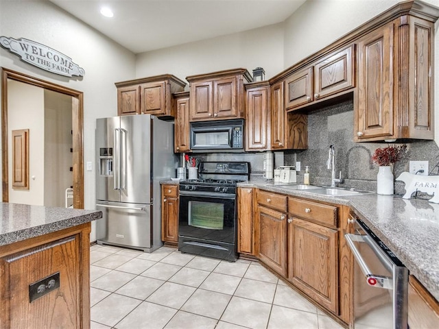 kitchen featuring tasteful backsplash, sink, light tile patterned floors, and black appliances