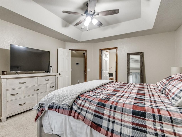 bedroom with a tray ceiling, light colored carpet, and ceiling fan