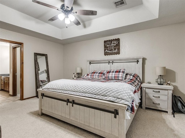 carpeted bedroom with a raised ceiling and ceiling fan