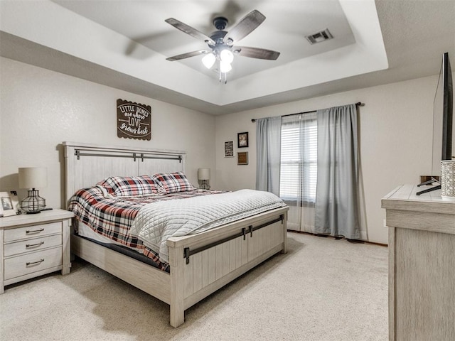 bedroom featuring ceiling fan, a raised ceiling, and light carpet