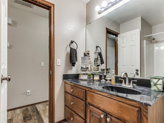 bathroom with walk in shower, vanity, and hardwood / wood-style floors