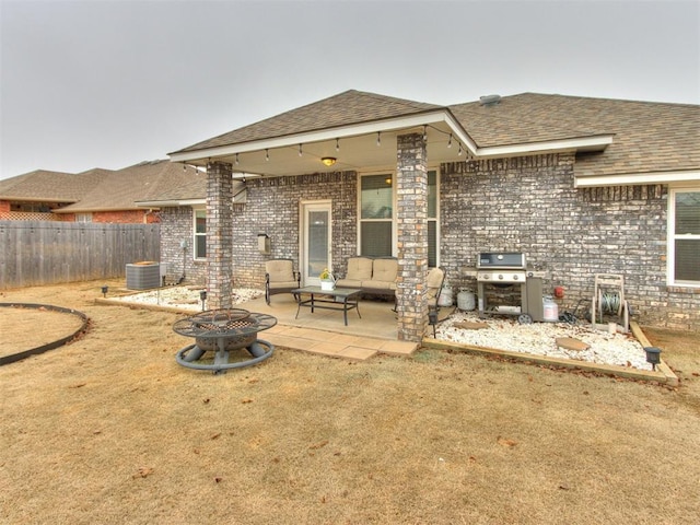 rear view of house with a yard, central AC, a patio area, and an outdoor fire pit