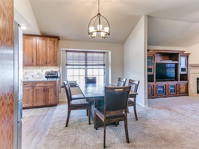 carpeted dining room featuring vaulted ceiling and a notable chandelier