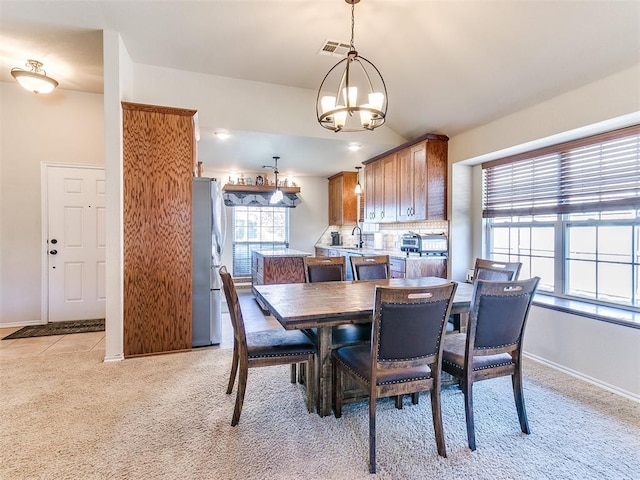 carpeted dining room featuring sink and a chandelier