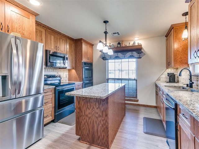 kitchen featuring a kitchen island, decorative light fixtures, sink, light stone counters, and stainless steel appliances