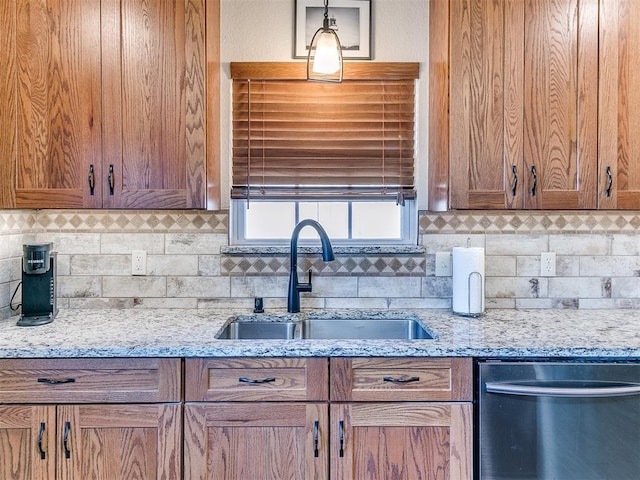 kitchen with pendant lighting, sink, light stone counters, and dishwasher