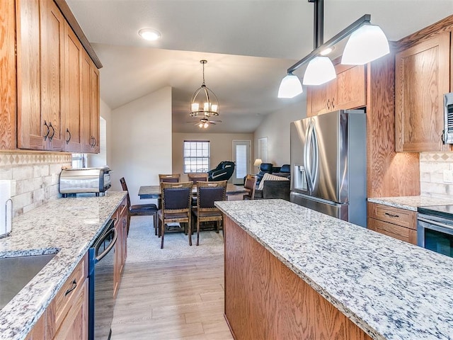 kitchen with hanging light fixtures, stainless steel appliances, a notable chandelier, light stone countertops, and vaulted ceiling