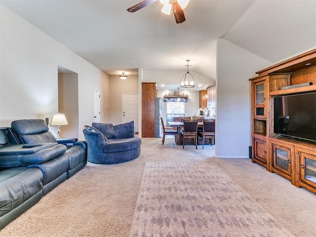 carpeted living room featuring ceiling fan with notable chandelier and vaulted ceiling